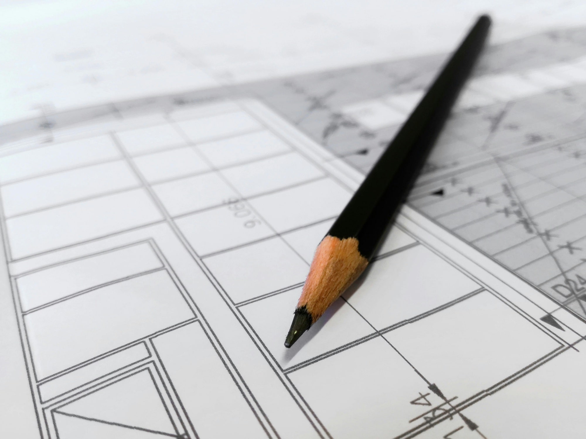 A pencil rests on a blueprint, indicating a design or architectural plan in progress.